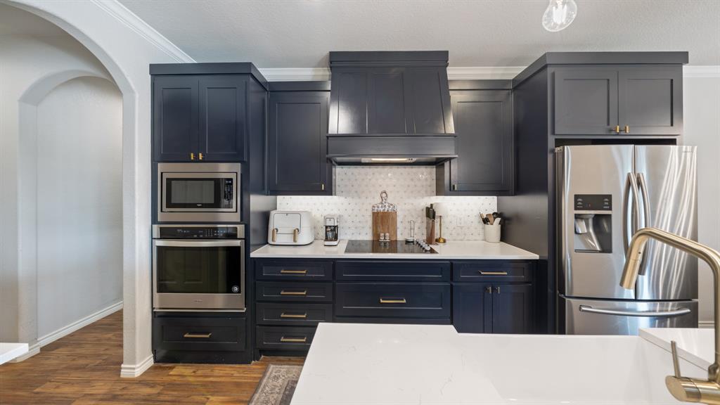 101 Lighthouse Lane Mabank, TX 75143 - Photo 14 of 40 Kitchen featuring stainless steel appliances, tasteful backsplash, light stone countertops, dark wood-style flooring, and crown molding