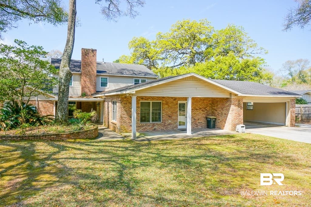 255 Suffolk Road Mobile, AL 36608 - Photo 7 of 29 Back of property with brick siding, a yard, a carport, and driveway