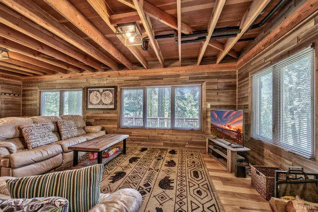 a living room with furniture a flat screen tv and a floor to ceiling window