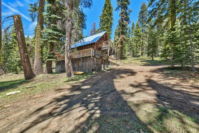 a backyard of a house with large trees and wooden fence