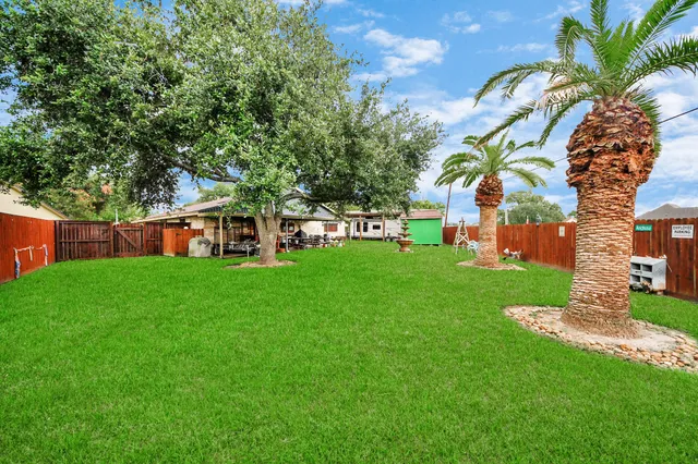 a view of a house with a big yard plants and large trees