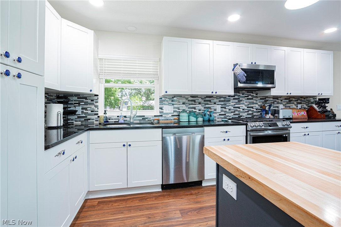 2055 Ganyard Road Akron, OH 44313 - Photo 13 of 49 Kitchen with white cabinetry, stainless steel appliances, dark hardwood / wood-style floors, decorative backsplash, and sink
