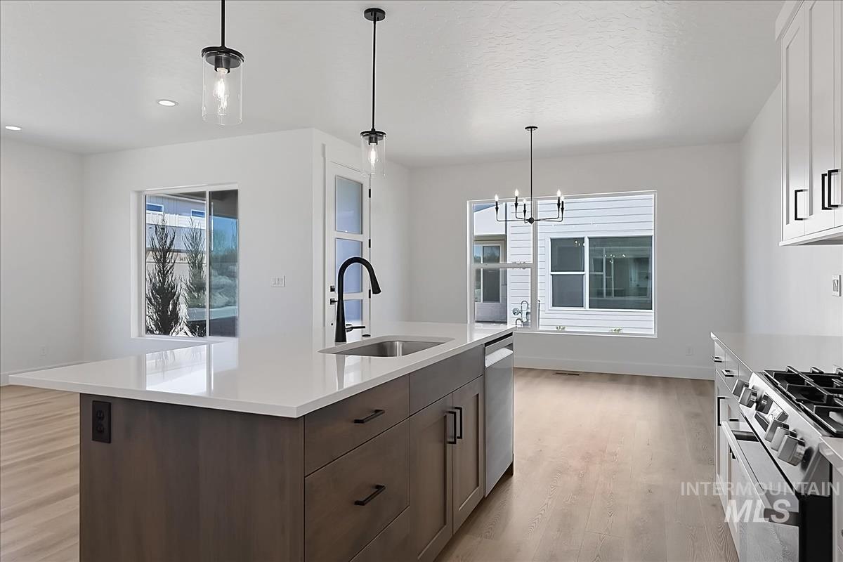776 South Calhoun Lane Star, ID 83669 - Photo 8 of 49 Modern kitchen featuring a central island with a sink and quartz countertop, stainless steel appliances, and light wood-finish flooring