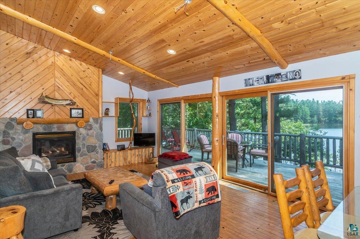 11758 South Long Lake Road Solon Springs, WI 54873 - Photo 12 of 38 Living room with a stone fireplace, wood walls, wooden ceiling, hardwood / wood-style flooring, and lofted ceiling with beams