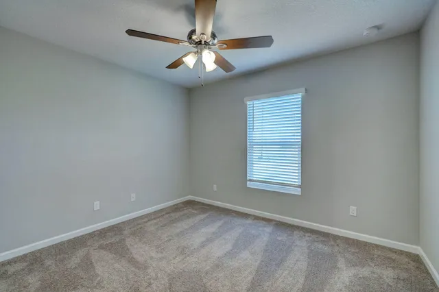 an empty room with windows and ceiling fan