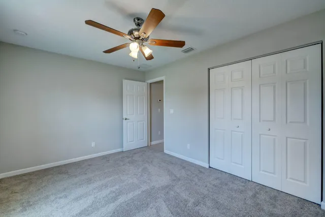 an empty room with closet and a chandelier fan