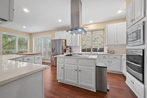 a large kitchen with kitchen island granite countertop a large window a sink stainless steel appliances and cabinets