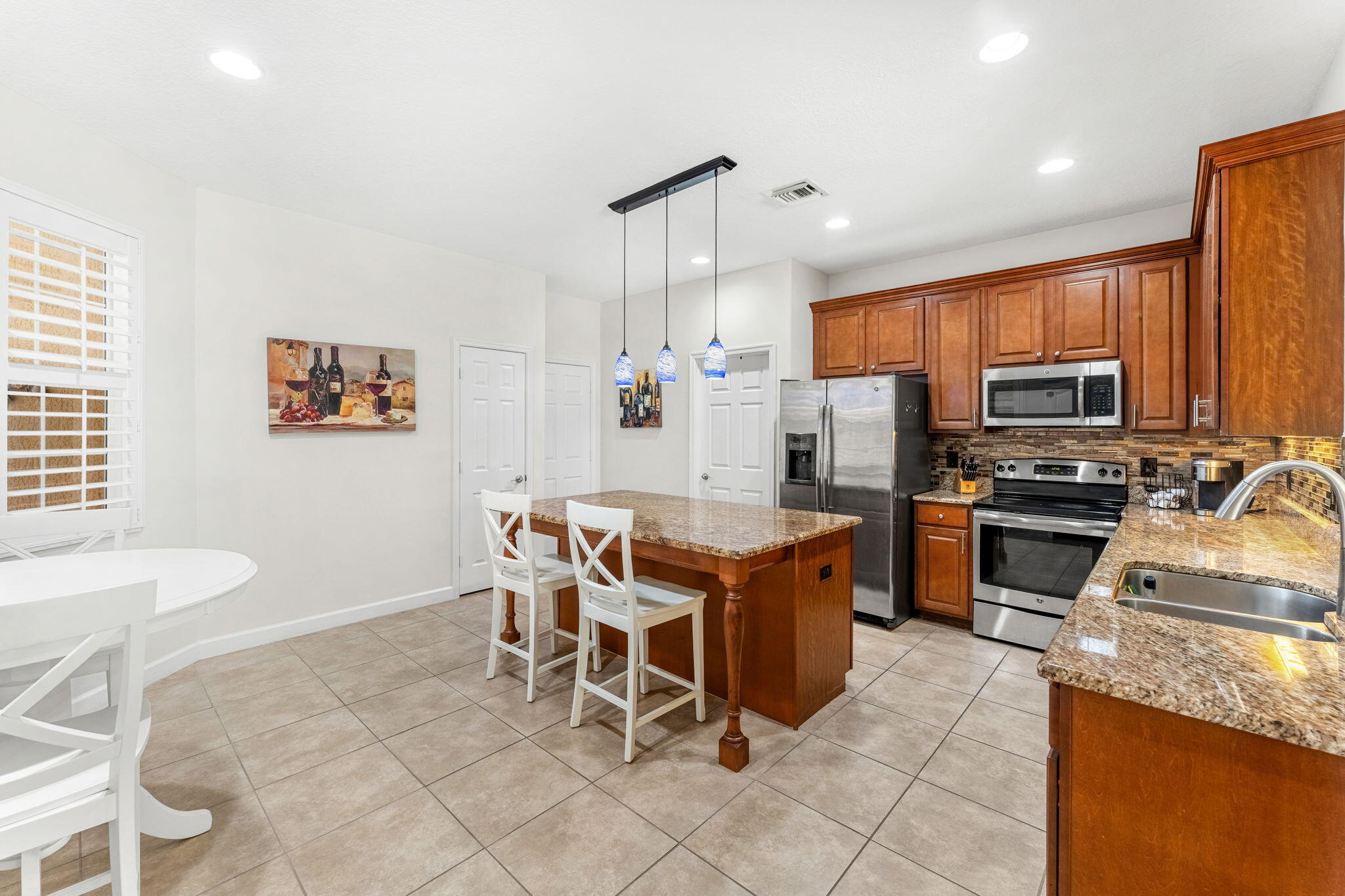 7657 Fieldstone Ranch Square Vero Beach, FL 32967 - Photo 16 of 52 a kitchen with stainless steel appliances granite countertop a stove a sink a refrigerator dining table and chairs