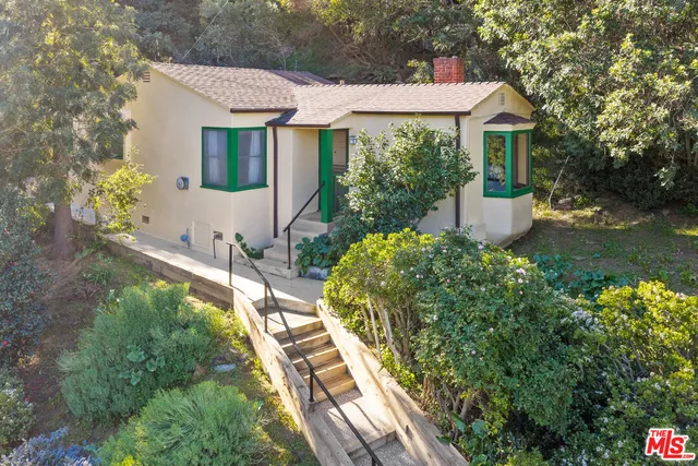 a front view of a house with a yard and potted plants