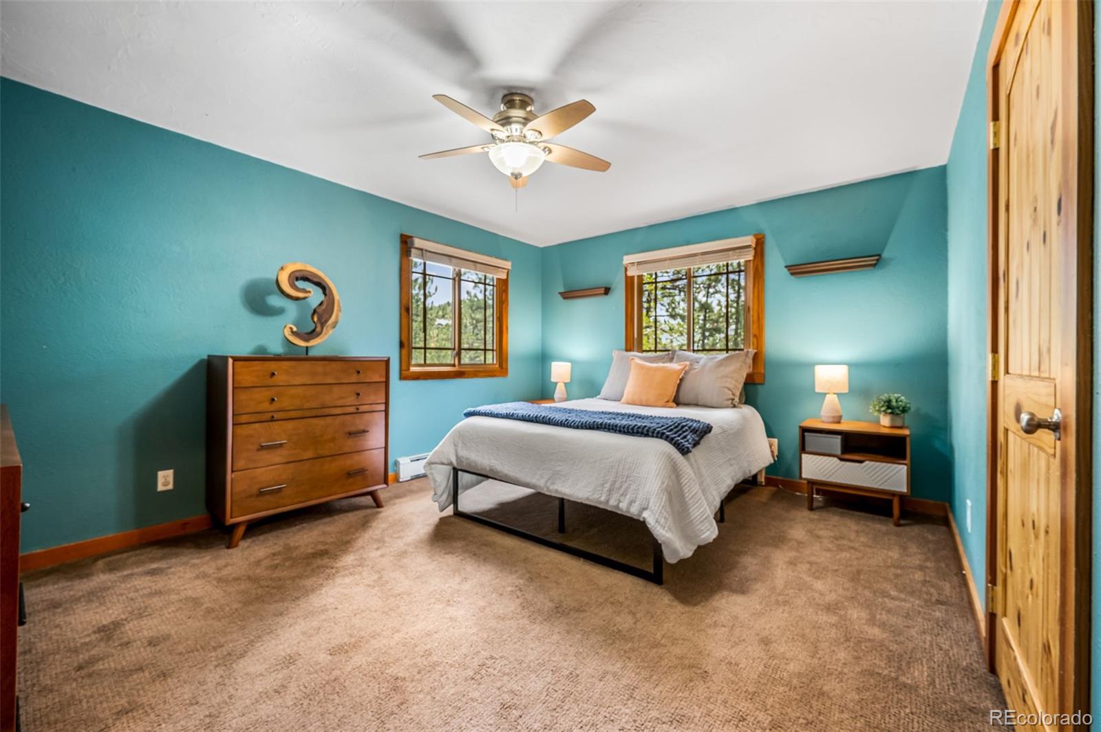 30315 Lone Spruce Road Evergreen, CO 80439 - Photo 16 of 48 a spacious bedroom with a bed and a chandelier
