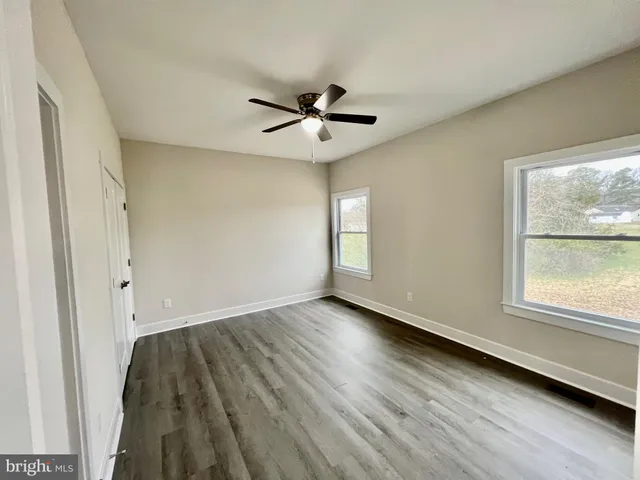 a view of empty room with wooden floor and fan