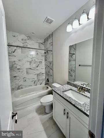 a bathroom with a granite countertop toilet a sink and bathtub