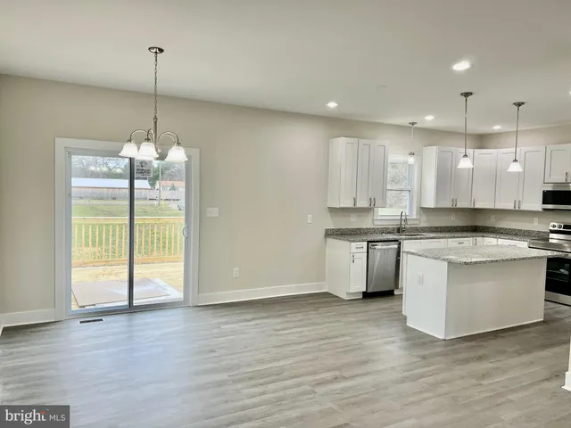 a kitchen with kitchen island granite countertop a stove a sink and a wooden floors