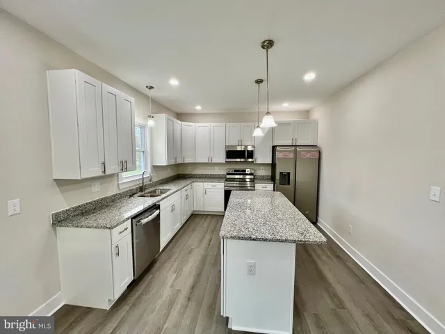 a large kitchen with granite countertop a counter space stainless steel appliances and cabinets