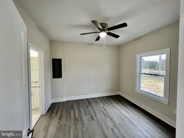 a view of empty room with wooden floor and fan