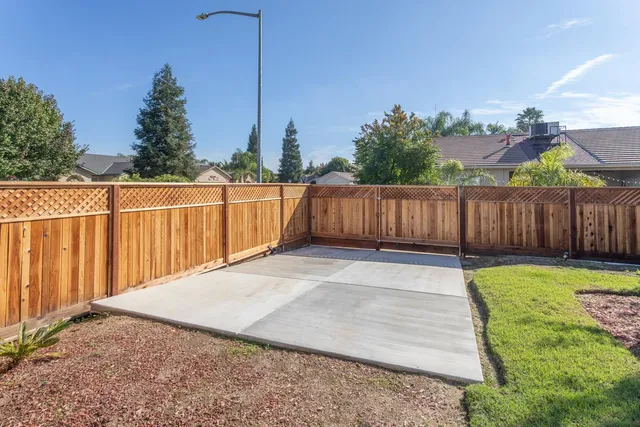 a view of a backyard with table and chairs potted plants and wooden fence