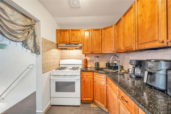 a kitchen with granite countertop a stove top oven sink and cabinets