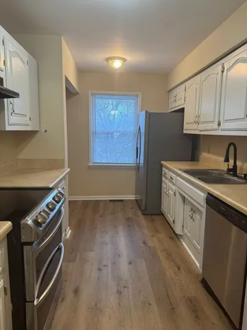 a kitchen with cabinets wooden floor and stainless steel appliances
