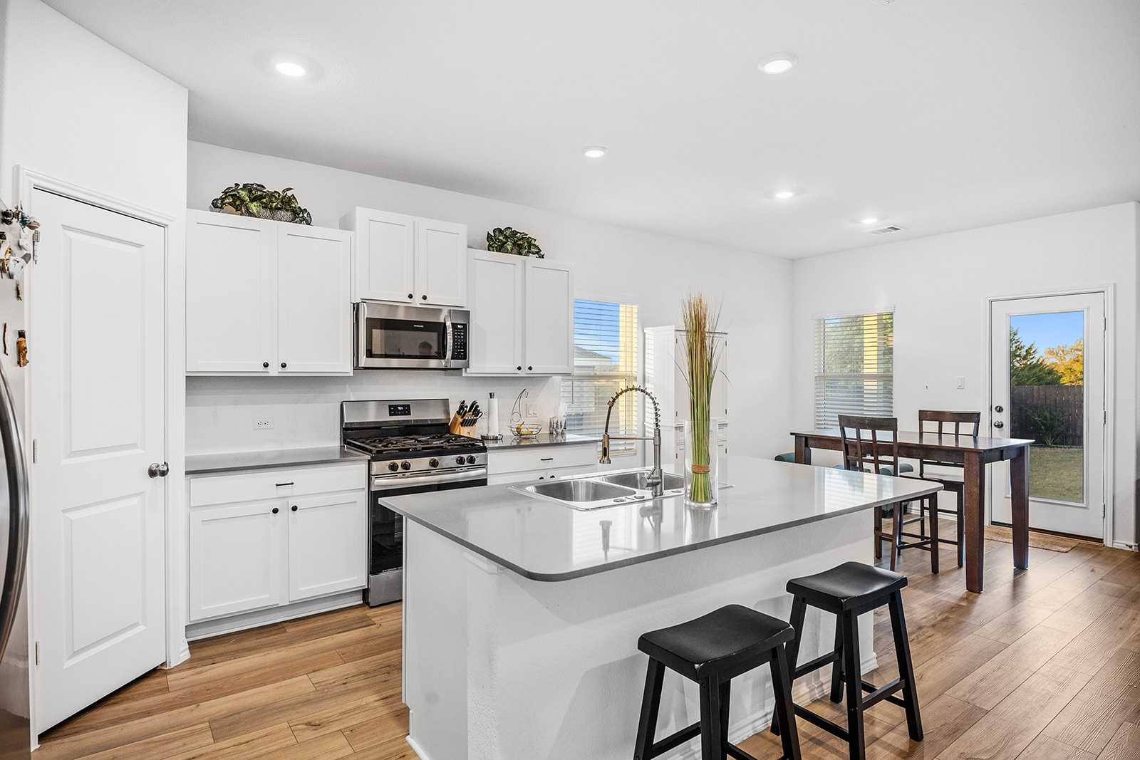 1909 Four Waters Loop Georgetown, TX 78628 - Photo 7 of 35 a kitchen with stainless steel appliances granite countertop a stove top oven a sink a refrigerator and white cabinets with wooden floor