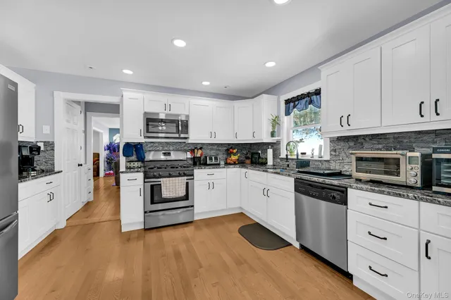 a kitchen with granite countertop white cabinets and stainless steel appliances