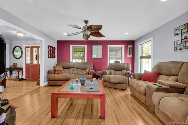 a living room with furniture a large window and wooden floor