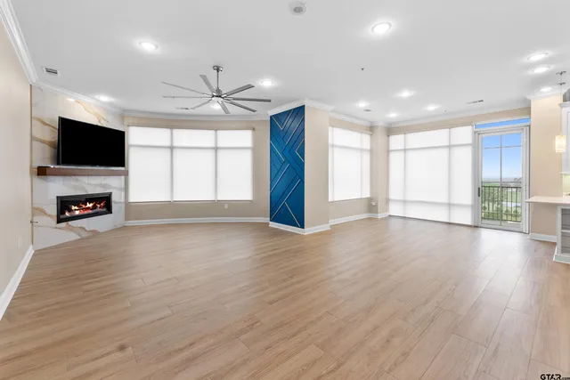 an empty room with windows flat screen tv and wooden floor