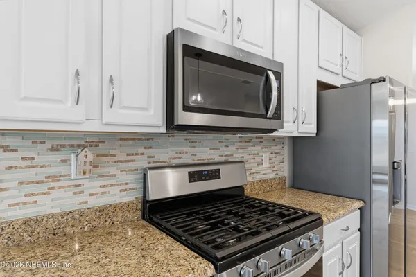 a kitchen with granite countertop stainless steel appliances a stove a microwave and cabinets