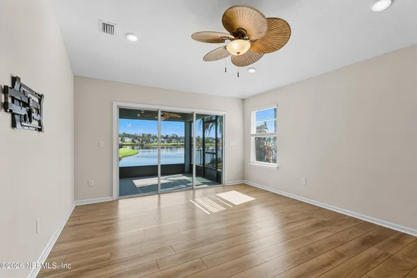 a view of an empty room with a window and wooden floor