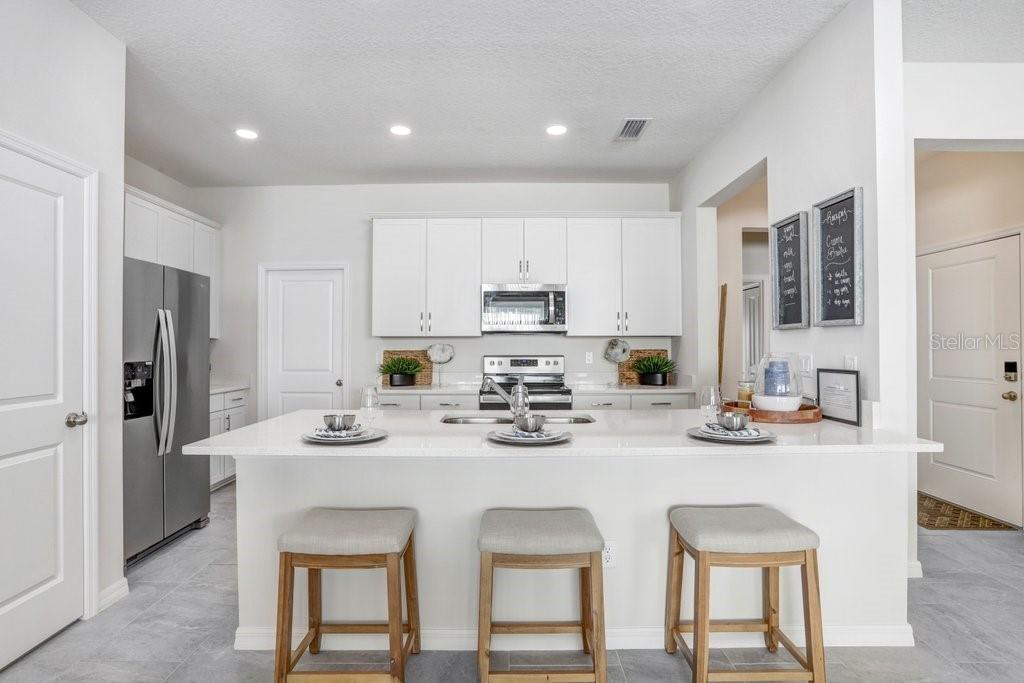 5349 Coldpine Place Seffner, FL 33584 - Photo 8 of 24 a kitchen with stainless steel appliances kitchen island granite countertop a dining table chairs and refrigerator