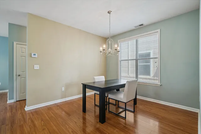 a view of a workspace room with wooden floor table and chairs