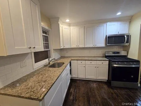 a kitchen with stainless steel appliances granite countertop a stove a sink and a microwave
