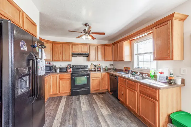 a kitchen with stainless steel appliances granite countertop a refrigerator a sink dishwasher a stove and white countertops with wooden floor