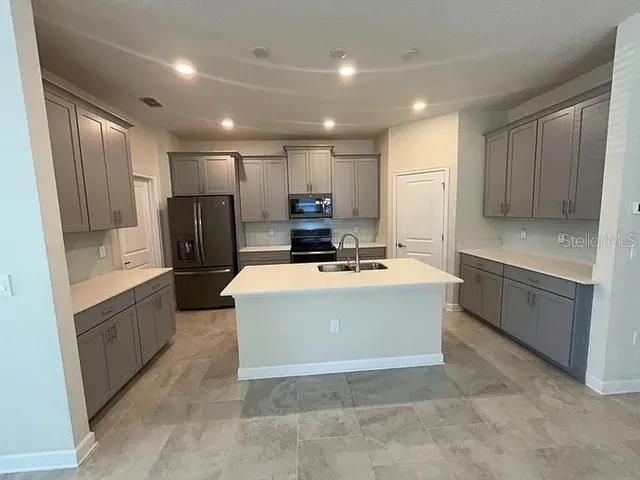 a kitchen with kitchen island a counter top space a sink stainless steel appliances and cabinets