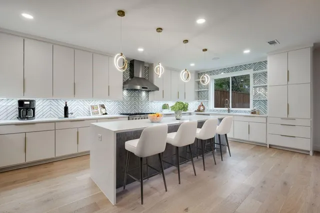 a kitchen with stainless steel appliances kitchen island wooden floors and white cabinets