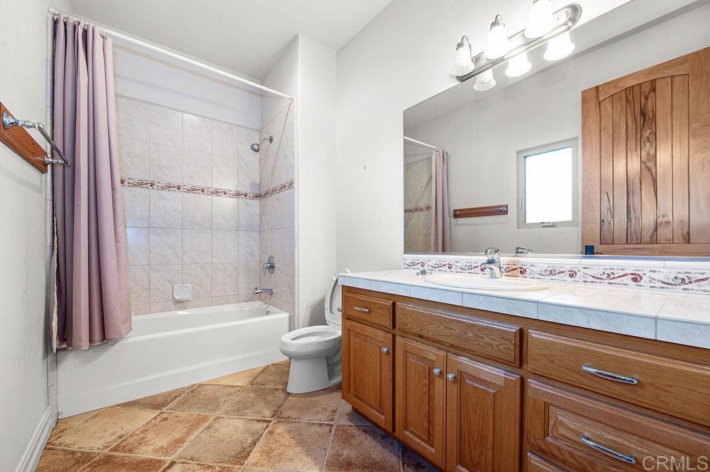 2155 Mil Sorpresas Drive Fallbrook, CA 92028 - Photo 30 of 48 a bathroom with a granite countertop sink a toilet a mirror and shower