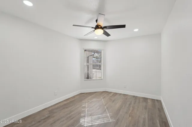 an empty room with a window and ceiling fan