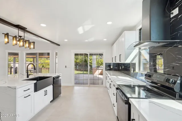 a large white kitchen with stainless steel appliances granite countertop a stove and a sink