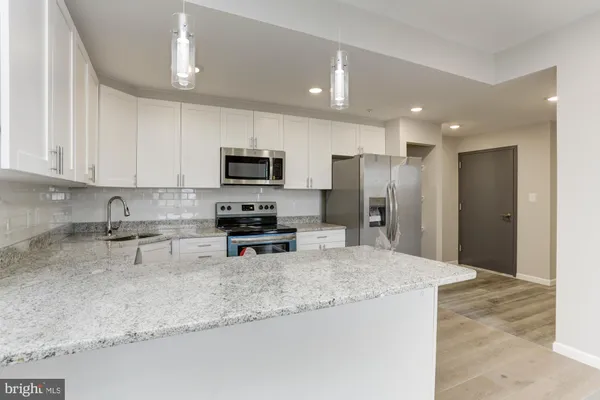 a kitchen with stainless steel appliances granite countertop a sink refrigerator and microwave