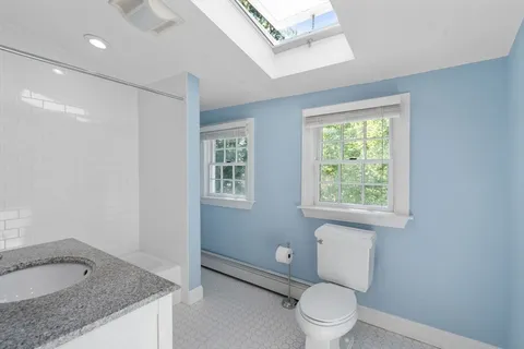 a bathroom with a granite countertop sink a toilet and a window