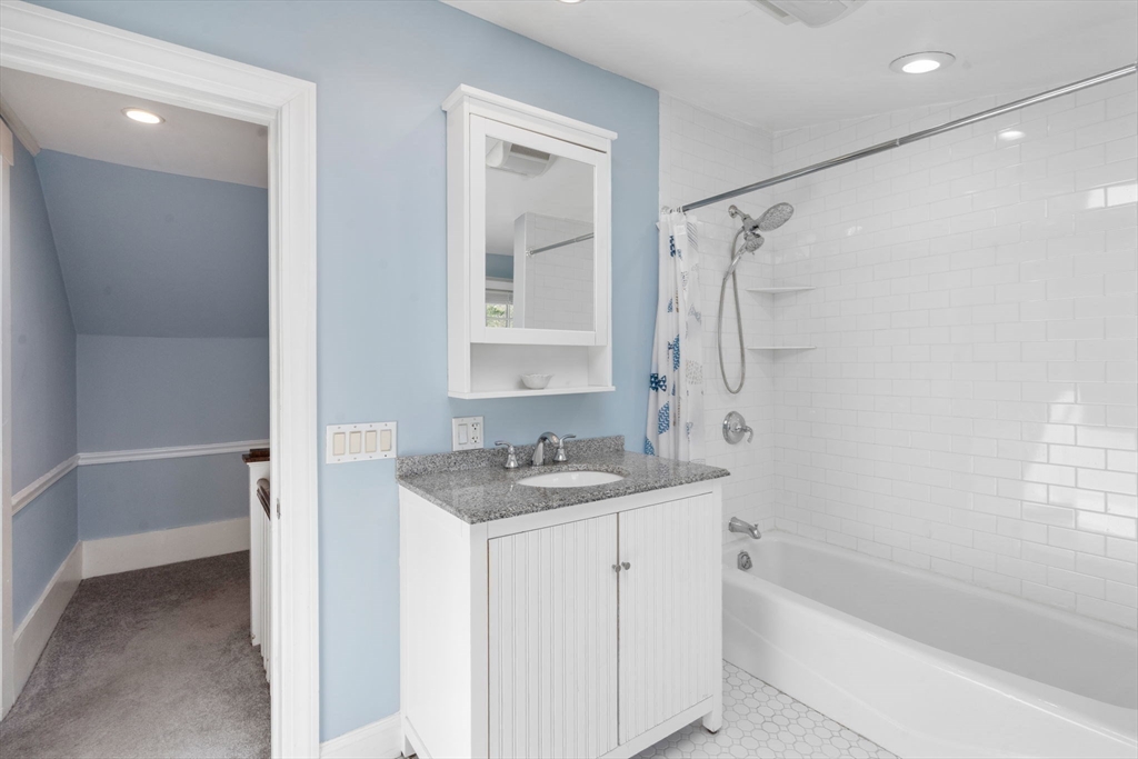513 Chestnut Street Newton, MA 02468 - Photo 19 of 32 a bathroom with a granite countertop sink a mirror a bathtub and shower