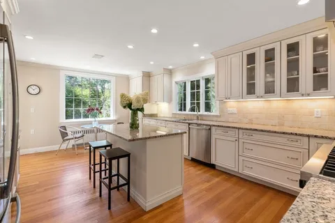 a kitchen with granite countertop a stove a sink a dining table and chairs