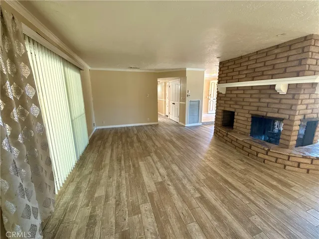 a view of empty room with wooden floor and fireplace