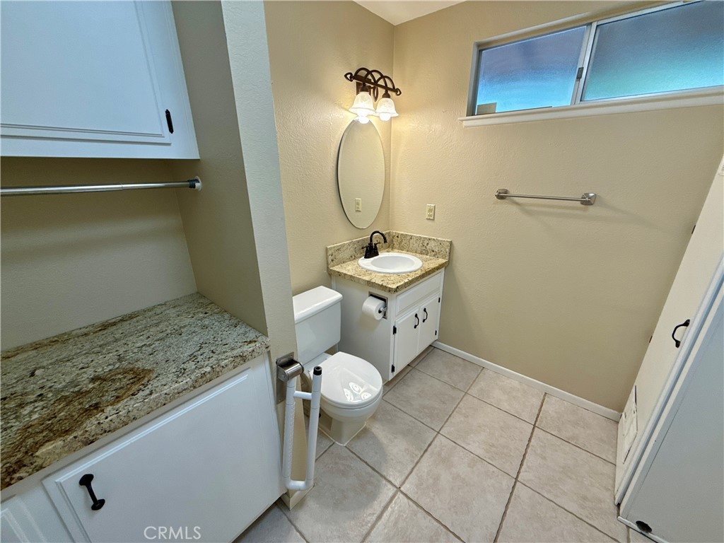 14705 Mandan Road Apple Valley, CA 92307 - Photo 9 of 20 a bathroom with a granite countertop sink a toilet and a mirror