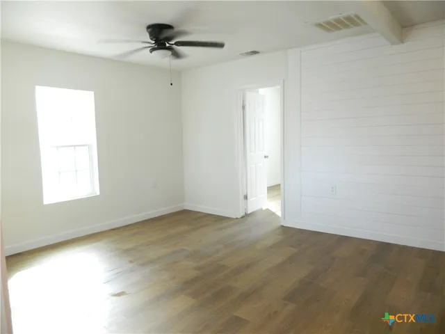 an empty room with a window and a ceiling fan