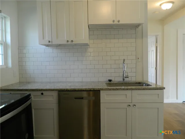 a sink with granite countertop cabinets