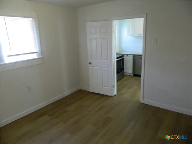 an empty room with wooden floor closet and windows