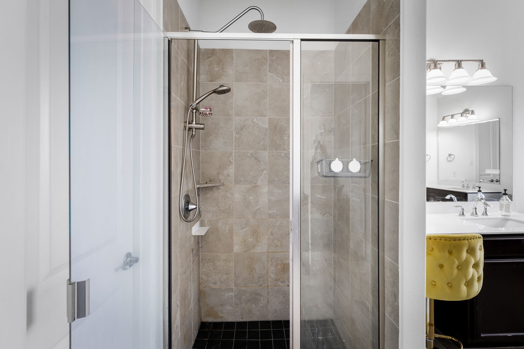 140 Waterloo Cove Georgetown, TX 78628 - Photo 23 of 40 A sleek, tiled walk-in shower features a rain head and hand-held shower, complementing the vanity beyond.