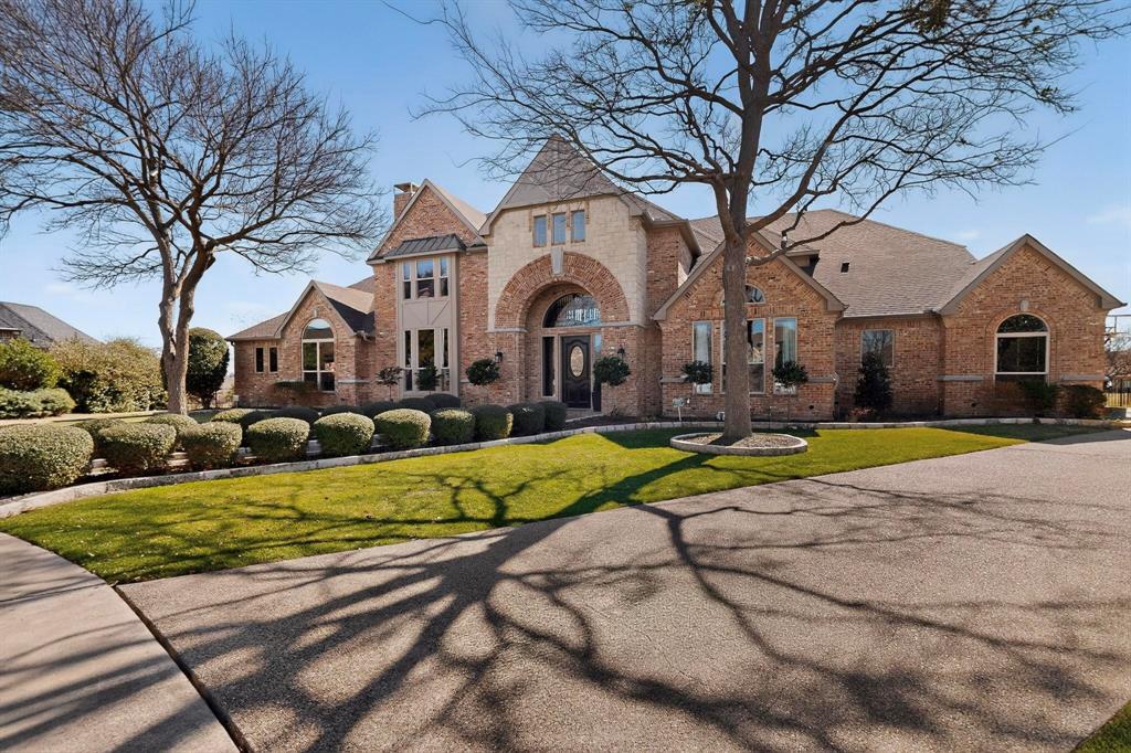 2108 Kyle Circle Heath, TX 75032 - Photo 39 of 40 Brick and stone exterior featuring an arched entryway, multiple gables, and a mature tree-lined front yard