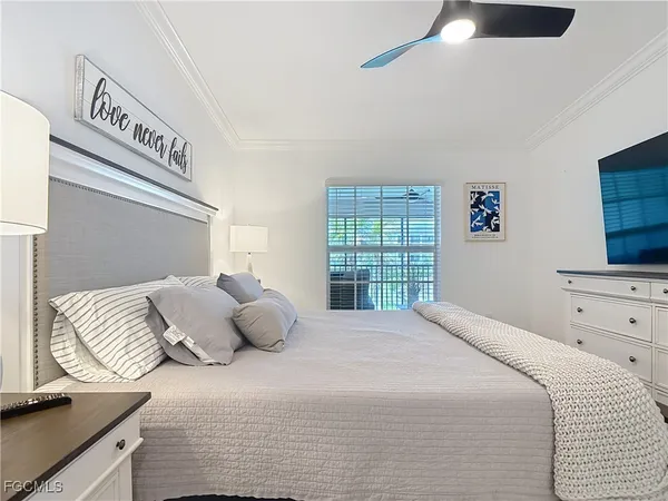 a bedroom with a bed tv and a window