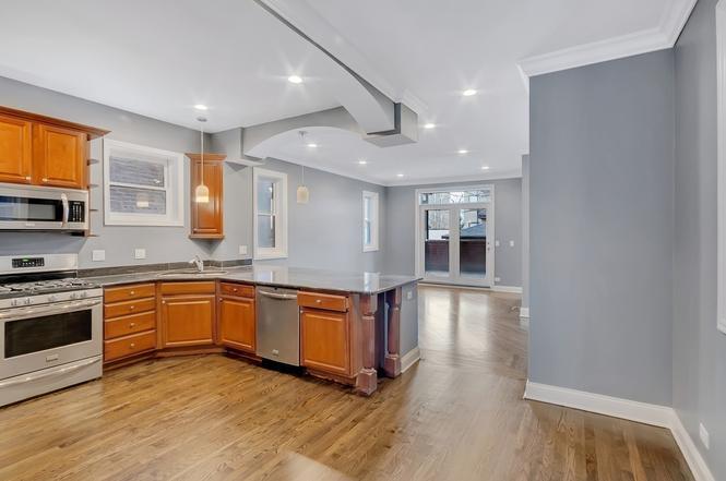 2417 West Fillmore Street, Unit 1 Chicago, IL 60612 - Photo 6 of 16 a large kitchen with stainless steel appliances granite countertop a stove and a sink